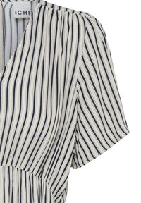 Blouse blanche à rayures noires verticales, manches courtes bouffantes et détail de taille froncée.