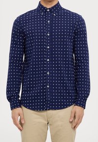 Námorně modrá košile s dlouhým rukávem s malým bílým čtverečkovaným vzorem, s límcem na knoflíky a předními knoflíky, vyrobená z měkké tkaniny.