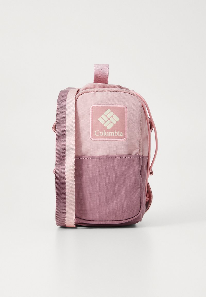 Mochila Columbia em rosa, com exterior de tecido, formato retangular, tons contrastantes e um logo em patch na frente.