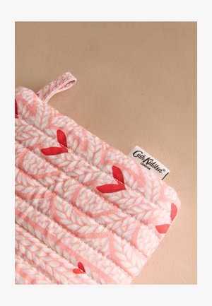 Roosa tepitud kangast potihoidja valgete lehemustrite ja punaste aktsentidega, millel on riputuslõng ja Cath Kidston London silt.