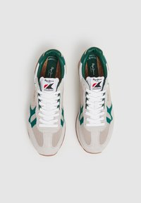 Sneakers con tomaia in rete beige e suede, dettagli verdi, lacci bianchi e suola in gomma marrone. Marchio visibile sulla linguetta.