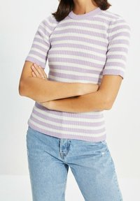 Gestreifter Kurzarmpullover in Lavendel und Weiß, mit Rippenstruktur, rundem Ausschnitt, figurnaher Silhouette, kombiniert mit ausgewaschenen hellblauen Jeans.