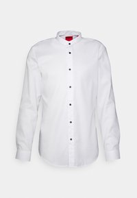 Camicia da uomo a maniche lunghe di colore bianco con bottoni neri e etichetta rossa "HUGO" all'interno del colletto, esposta su uno sfondo bianco.