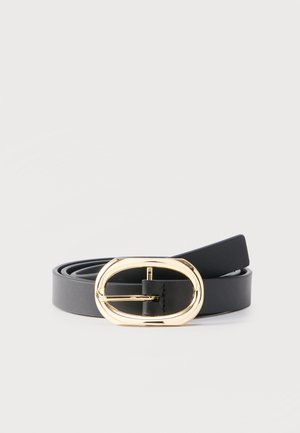 Črni usnjen pas s sijočo zlato ovalno sponko, zvit na enostavni svetlo sivi podlagi.