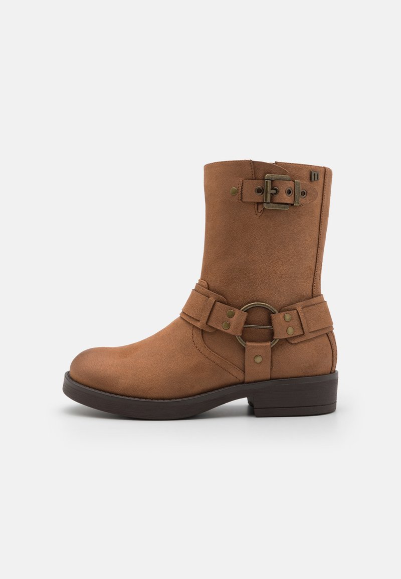 Bottine en suède marron avec un bout arrondi, une sangle et une boucle, et un petit talon empilé. Présente une surface texturée et des accents métalliques.