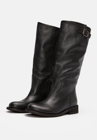 Bottes hautes en cuir noir avec une texture lisse, bout rond et une boucle décorative sur le côté. Semelle plate et robuste.