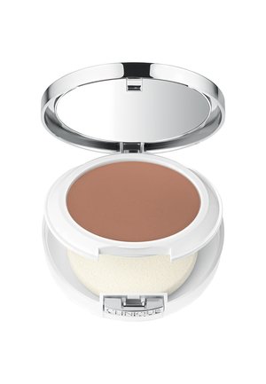 Bronzer compact avec une surface lisse et mate dans une teinte bronzée profonde. Présente un boîtier circulaire blanc avec un miroir et un applicateur en éponge.