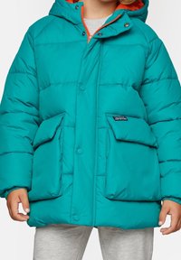 Tyrkysová prošívaná bunda s odnímatelnou kapucí, s oranžovými detaily, patentními knoflíky a dvěma velkými předními kapsami. Měkká, prošívaná textura.