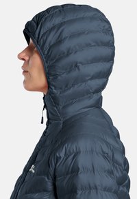 Veste matelassée légère isolée en bleu marine foncé, dotée d'un design matelassé, d'une capuche attachée et d'une fermeture éclair avec tirette à bascule.