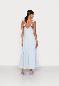 Šviesiai mėlynas, be rankovių maksi suknelė su pūstomis petnešomis, su juosmens įtempimu ir sluoksniuotu sijonu. Nugarinėje dalyje yra reguliuojami raišteliai.