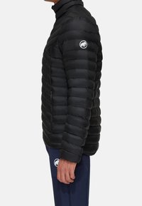 Zwarte pufferjas met hoge kraag, voorzien van een horizontaal gestikt ontwerp, ritszak aan de zijkant en logo-opdruk op de linker schouder.
