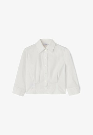 Camisa blanca corta con mangas tres cuartos, cuello puntiagudo y detalles plisados debajo del pecho sobre un fondo liso.