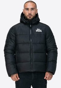 Czarna puchowa kurtka z zapięciem na zamek i kapturem. Posiada poziome pikowane sekcje oraz białe logo na lewej piersi.