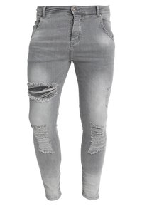 Jeans de denim gris con un corte ajustado, que presentan desgastes y rotos en ambas rodillas, diseño clásico de cinco bolsillos y cierre de botón metálico.