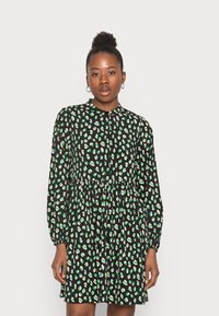 Vestido preto com estampa animal em verde e creme, mangas compridas, frente abotoada, costura na cintura e um corte descontraído, feito de um tecido leve.