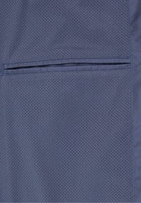 Tissu bleu avec de petits trous perforés présentant une poche horizontale fendue avec des coutures nettes et droites sur le côté droit.