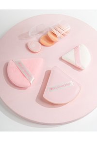 Set di quattro spugnette per trucco di forme diverse: rotonda, ovale e triangolare, in morbide tonalità di rosa pastello e pesca. Include una custodia trasparente per la conservazione.