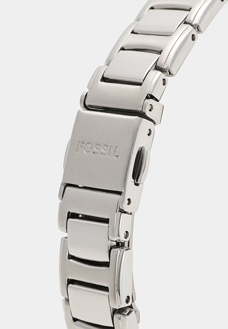 Cinturino in acciaio inossidabile argentato con maglie lucide e spazzolate, caratterizzato da una chiusura incisa con "FOSSIL" e una superficie liscia.