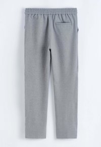 Pantalon de survêtement gris avec une taille élastique, des jambes fuselées et une poche arrière à rabat. Texture douce et fini lisse.