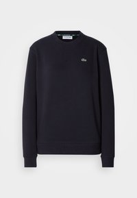 Sweat-shirt noir à manches longues avec col rond, logo crocodile vert Lacoste sur la poitrine gauche et poignets et ourlet côtelés.