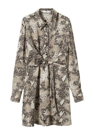 Femme portant une mini-robe boutonnée à manches longues avec un motif serpent et des sandales noires à talons hauts avec bride à la cheville, debout.