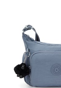 Borsa a spalla blu con tasca frontale, tracolla regolabile e un portachiavi gorilla in peluche nero attaccato alla cerniera.