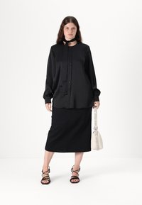 Black long-sleeve shirt with a neck tie, button front, paired with a black knee-length skirt and strappy black sandals. White handbag included.