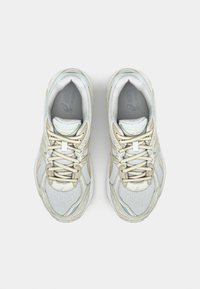 Ljusgrå träningsskor med mesh-överkonstruktion, beige detaljer och snören. Distinkt kurvad design och texturerad sula.