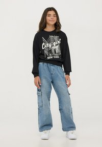 Felpa nera a maniche lunghe con grafica bianca "City girl New York" e pantaloni cargo baggy blu chiaro con tasche laterali e cordoncino.