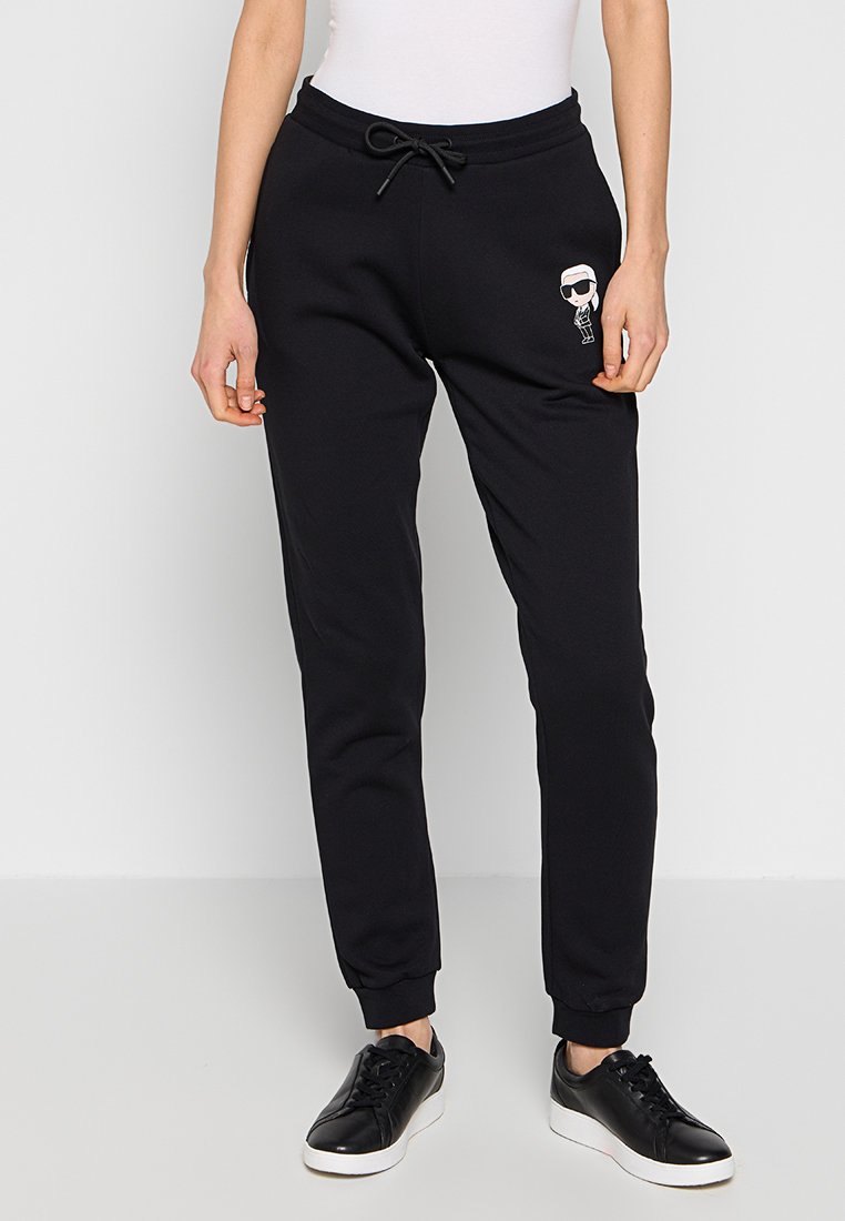 Pantalons de sport noirs avec une taille à cordon, arborant un personnage de dessin animé brodé à l'avant. Tissu doux et poignets fuselés.