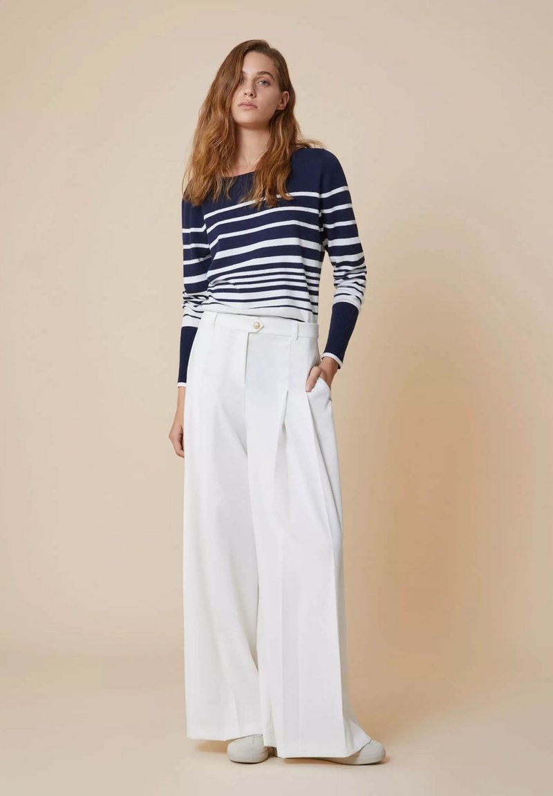 Navy-blauw en witte gestreepte lange mouwen trui gecombineerd met witte wijde broek; strak ontwerp met een knoopdetail en zijzakken.