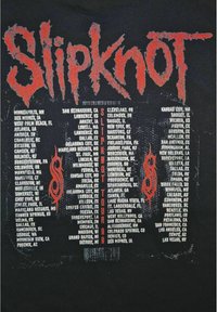 Sort t-shirt med "Slipknot" i rød, slidt tekst. Liste over turnébyer og stater trykt i hvid nedenfor. Små grafiske detaljer inkluderet.