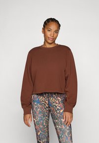 Sweatshirt marron court à manches longues, col rond et ourlets côtelés, associé à des leggings à motifs multicolores.