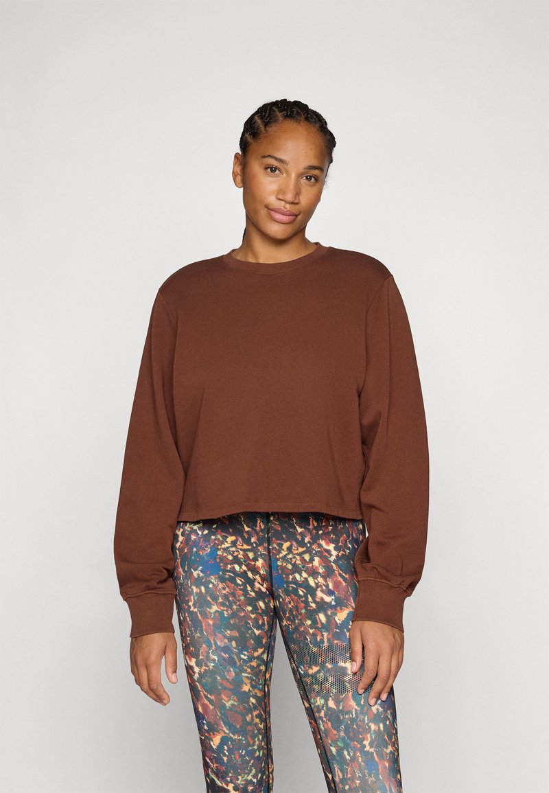 Sweatshirt marron court à manches longues, col rond et ourlets côtelés, associé à des leggings à motifs multicolores.