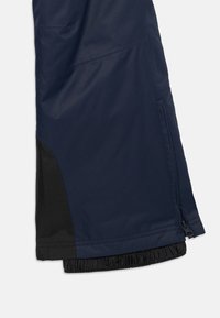 Mornarsko zunanje hlače z črnim panelom na robu, z žepom na zadrgo in elastičnim robom za udobno prileganje. Vidna teksturirana tkanina.