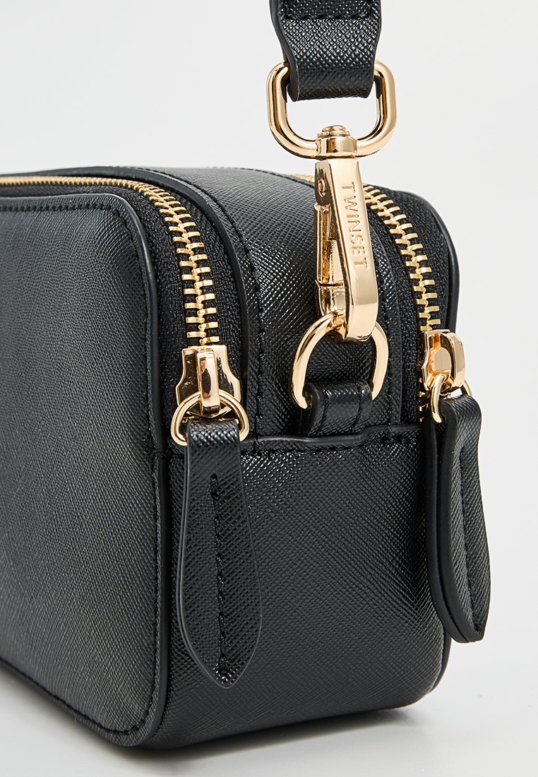 Czarna, teksturowana torba syntetyczna ze złotymi akcentami, wyposażona w podwójne suwaki i mały pasek, o prostokątnym kształcie z gładkim wykończeniem.