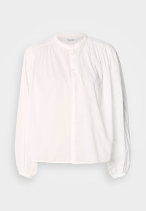 Blusa blanca de manga larga con cuello redondo, cierre de botones y detalles fruncidos en los hombros. Tela de algodón suave.