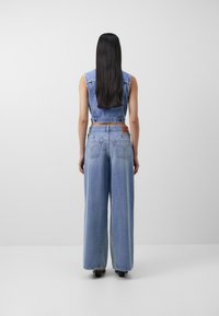 Džínové overaly s světle modrým odstínem, bez rukávů a širokými nohavicemi. Obsahují detaily na zadních kapsách a koženou značkovou visačku.