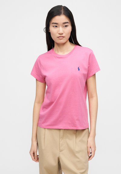 Rózsaszín pamut póló kerek nyakkivágással és rövid ujjakkal, kis kék hímzett logóval a bal mellrészen.