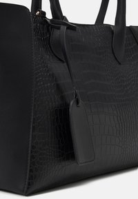 Czarna torebka na ramię z teksturowanym wzorem krokodyla z jednej strony, gładką skórą z drugiej oraz dwiema solidnymi uchwytami. Zawiera wymienny metek.