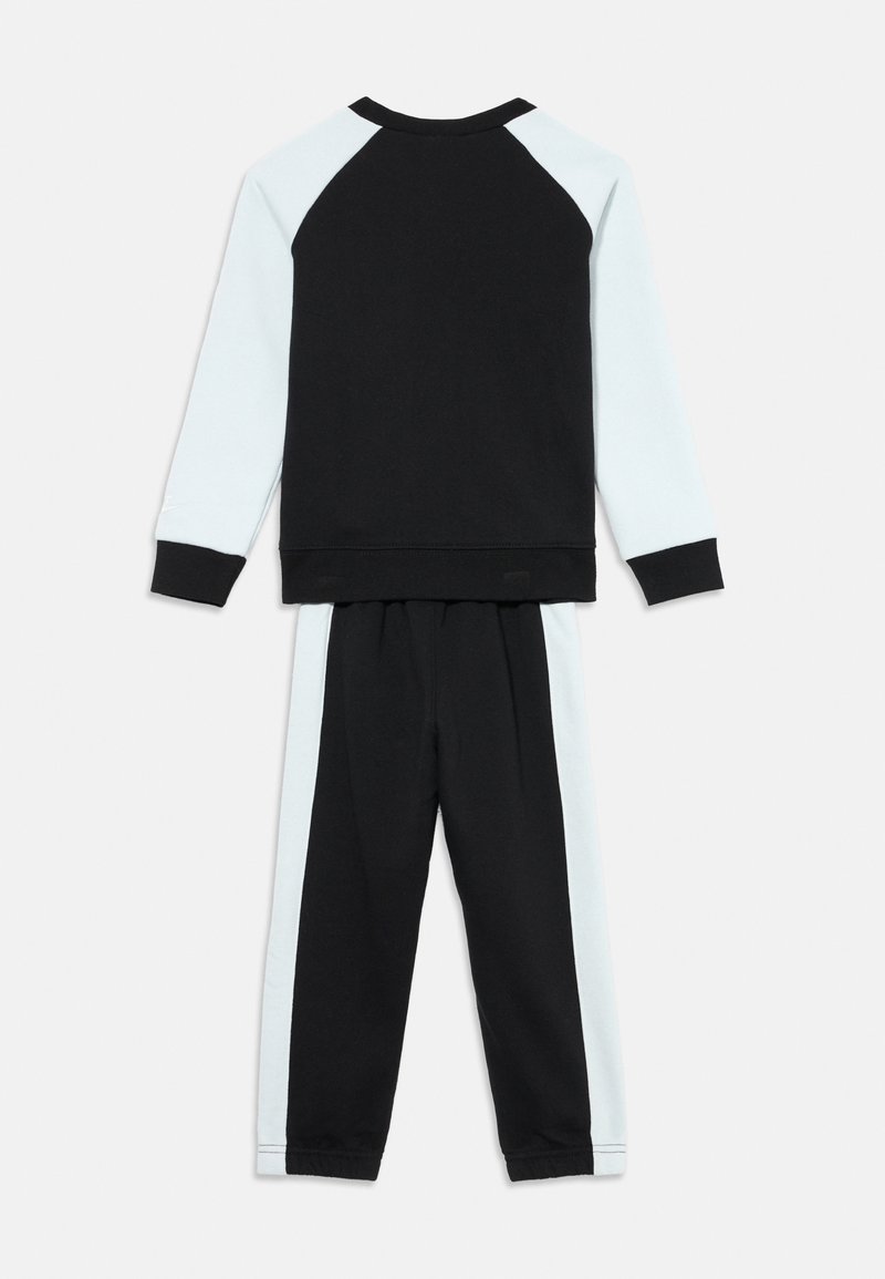 Tuta per bambini nera e azzurra chiara con maglia a maniche lunghe raglan e maniche a contrasto, abbinata a pantaloni con strisce laterali.