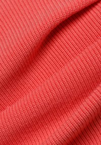 Korallenfarbener, gerippter Stoff mit einer weichen Textur, der auffällige vertikale Linien aufweist. Das Material wirkt dehnbar und leicht.