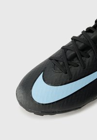 Fekete focicipő, textúrált felsőrésszel, világoskék Nike logóval. A fűzők feketék; a cipő áramvonalas formájú.