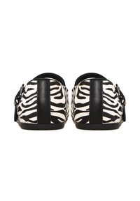 Loaferit, mille musta ja valget zebra mustrit, tekstuuriga viimistlusega, musta nahast aktsentiga kandmisel ja dekoratiivse klambriga külgedel.