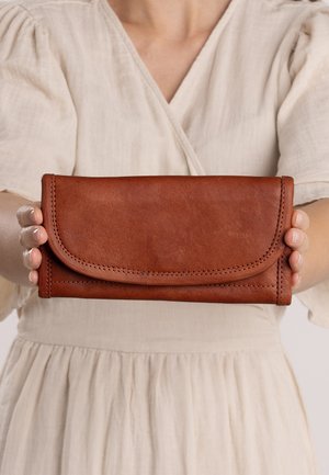 Brown leather wallet with a stitched edge and flap closure, held in hands. The wallet has a smooth texture and a rectangular shape.