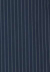 Tecido azul-marinho com riscas brancas verticais, composto por um material liso e tecido, apresentando uma textura uniforme e um espaçamento consistente entre as riscas.