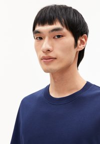 Marineblauwe t-shirt met korte mouwen en ronde hals, gemaakt van een zachte stof. Glad textuur, subtiele stikdetails op de halslijn.