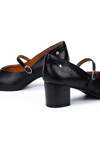 Chaussures en cuir noir avec un bout arrondi, dotées d'une sangle avec une boucle en métal et d'un dos texturé avec un motif crocodile, sur un talon carré.