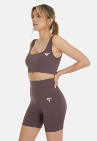 Braun Sport-BH und hochgeschnittene Shorts aus dehnbarem Material. Verfügt über eine gerippte Textur und ein kleines weißes Logo auf der linken Seite.