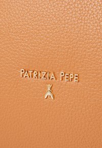 Pelle di colore tan con logo del brand in rilievo dorato "PATRIZIA PEPE" e un piccolo charm dorato come accent. Superficie liscia e resistente.